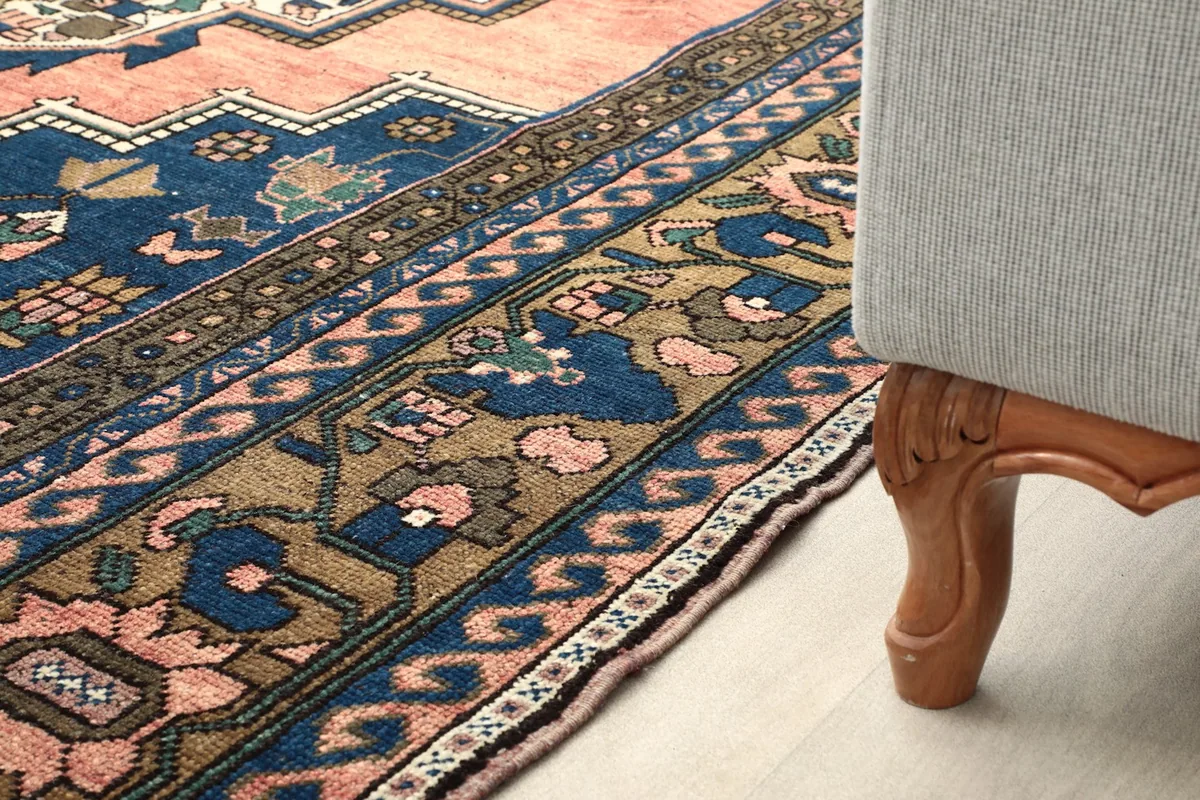 Rug detail next to a furniture leg, illustrating the low pile and border design in a room