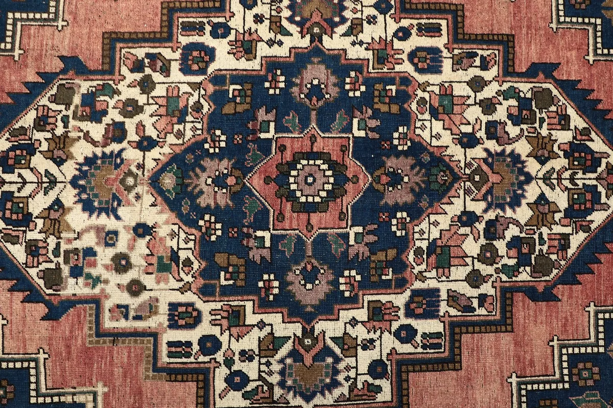 Detailed close-up of the central medallion and surrounding patterns in rose, navy, and ivory