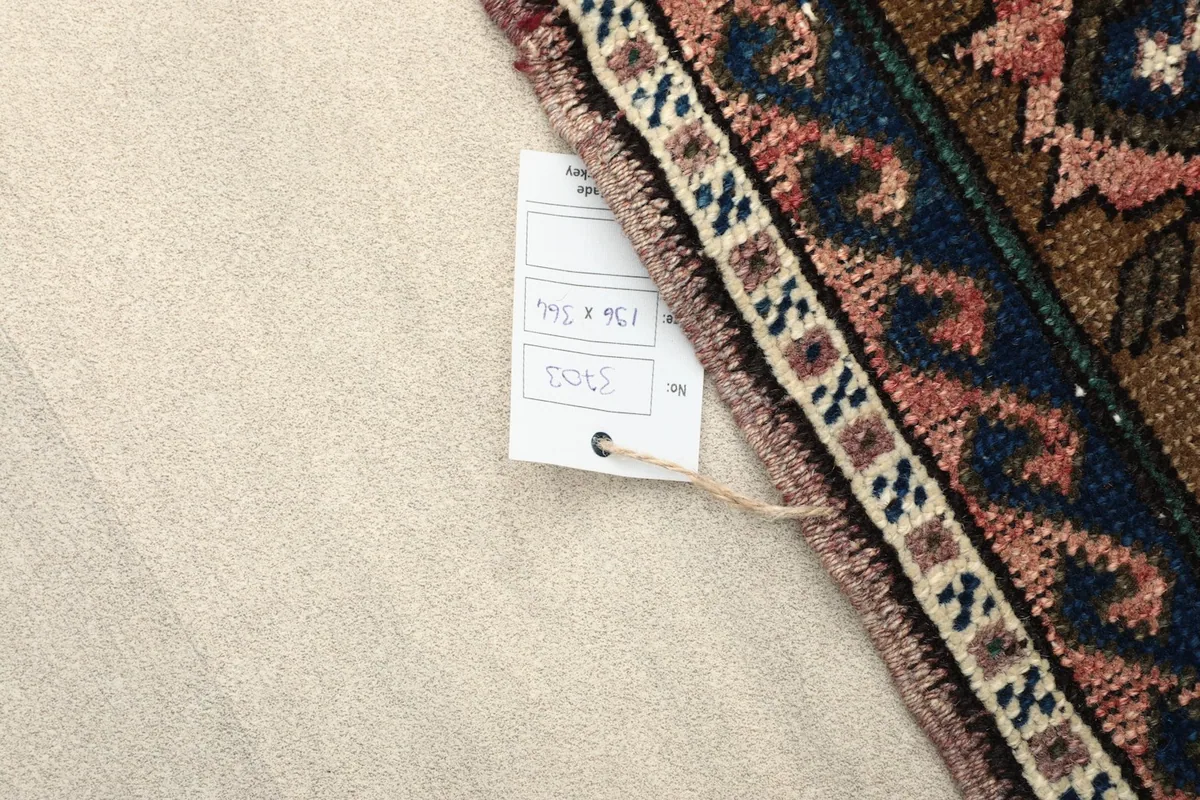 View of the rug's back and a label with measurements, highlighting the hand-knotted foundation