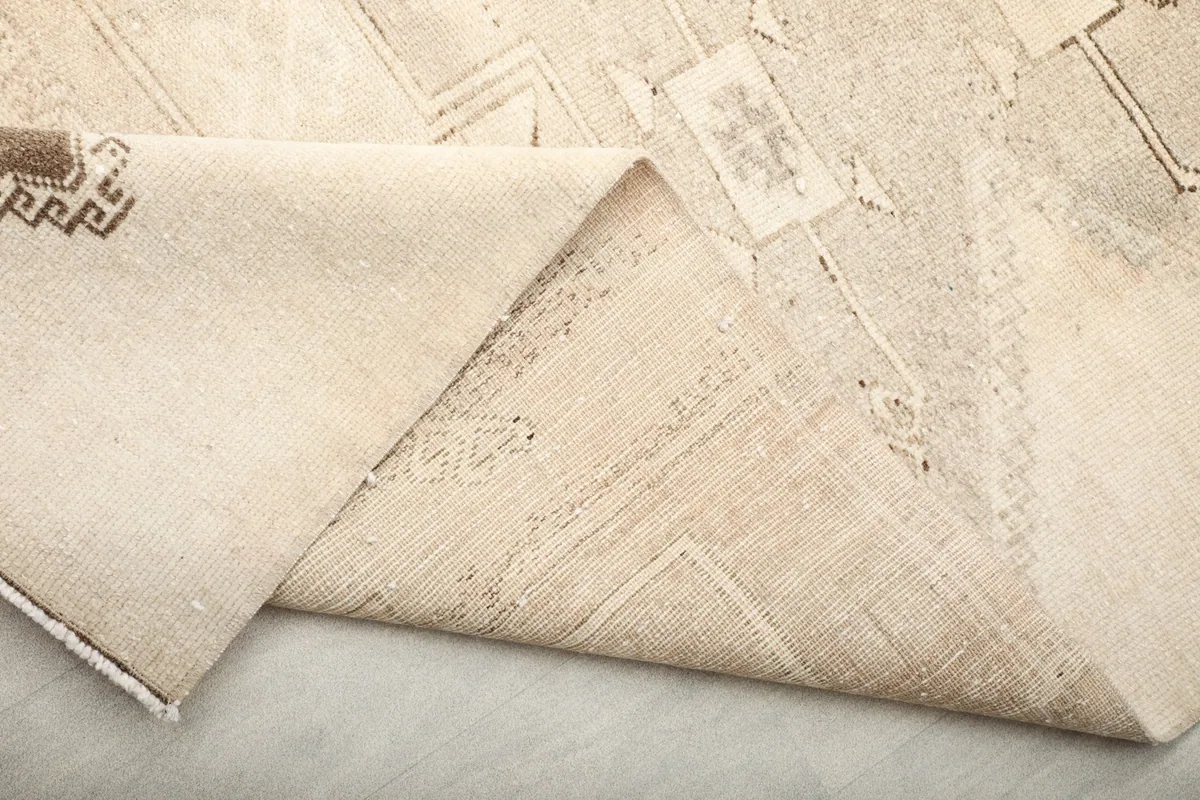 Close-up of the rug's low pile and the texture of the hand-knotted wool, with a glimpse of the foundation.