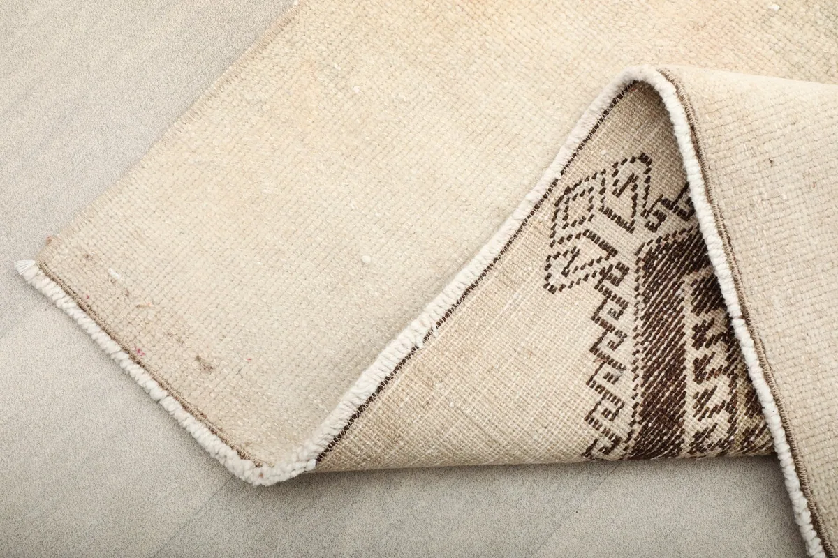 View of the rug's underside and folded edge, showing the cotton foundation and construction.