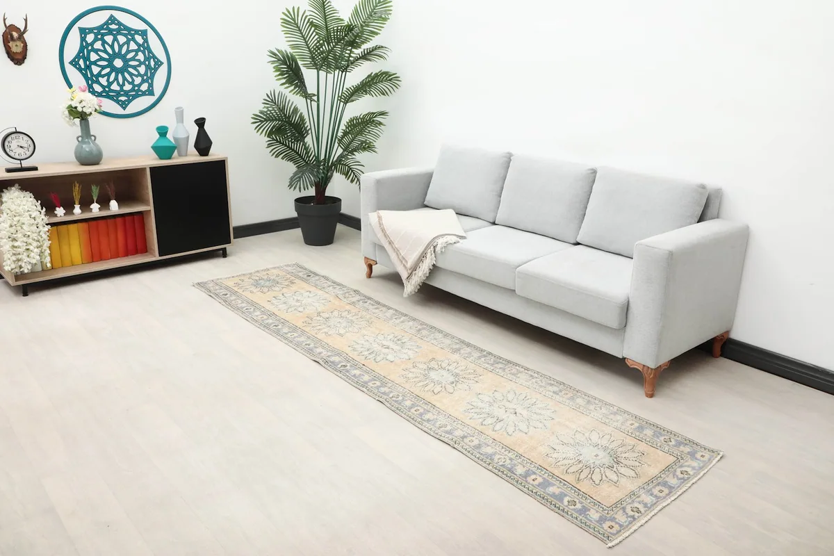 Wide shot of the beige runner rug in a living space with a sofa and decor, highlighting its scale.