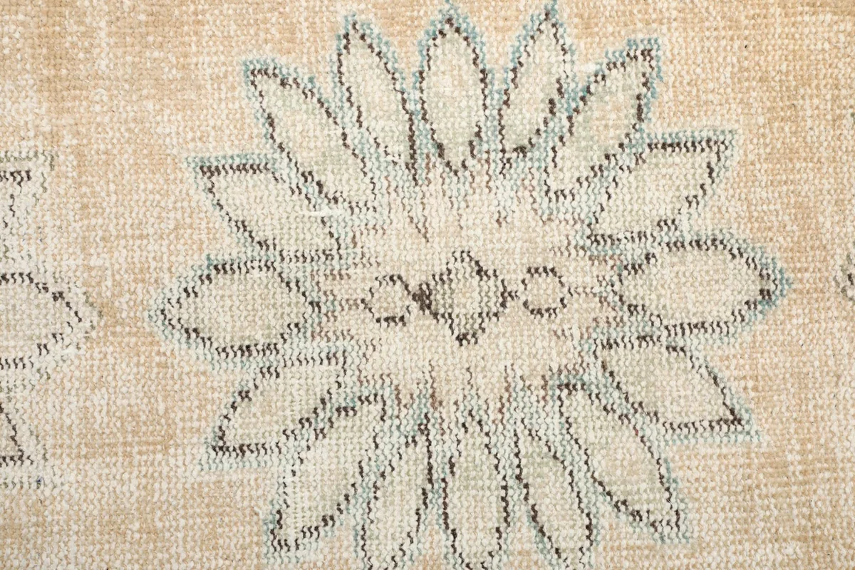 Close-up of the wool pile texture and a single faded floral medallion, revealing the hand-knotted detail.
