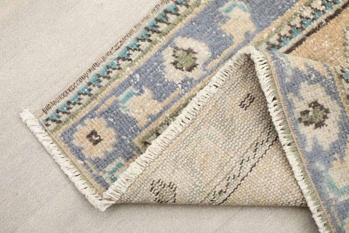 Detail of the rug's short, natural fringe and a section of the border, highlighting the knotting.