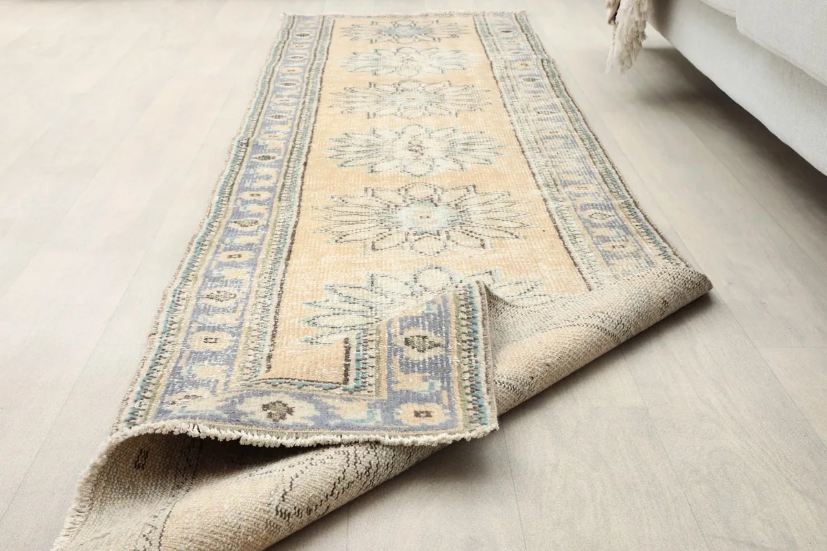 The runner rug with a corner folded back, revealing both the pile and the woven foundation.