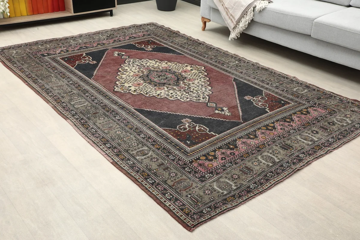 Close-up angled view of the rug in a room, focusing on the central design and surrounding patterns