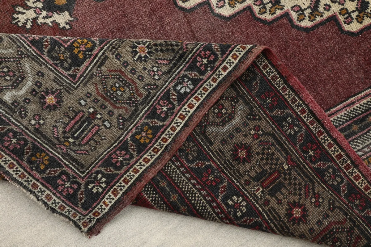 Folded corner of the rug, displaying the wool pile, cotton foundation, and intricate border design