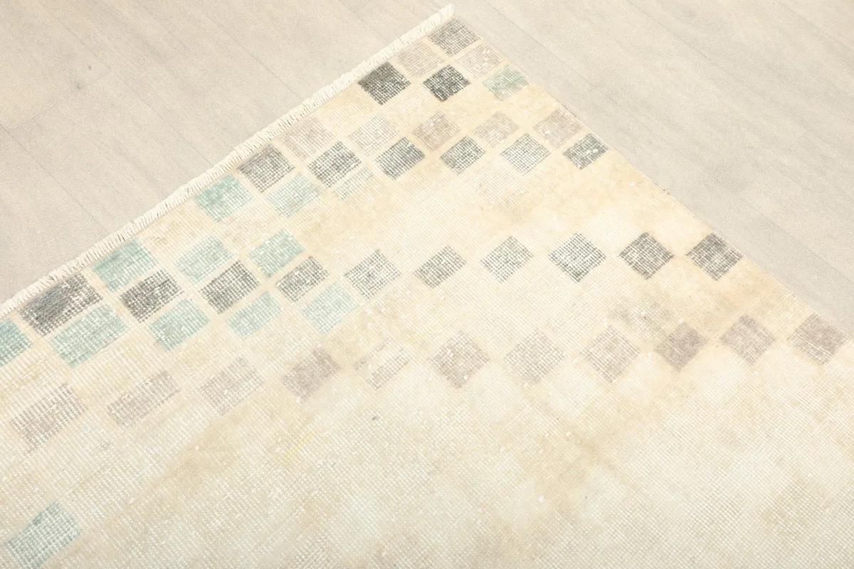 Corner view of the hand-knotted ivory rug showing the fading geometric pattern