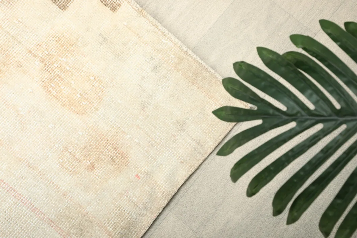 Overhead shot of a corner of the rug with a large green leaf, highlighting the ivory field