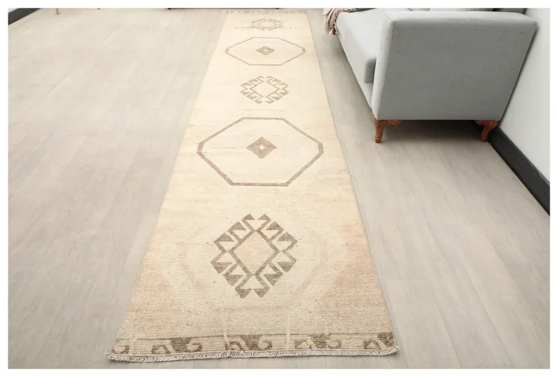 Full top view of the beige and tan geometric Anatolian runner rug on a light floor.