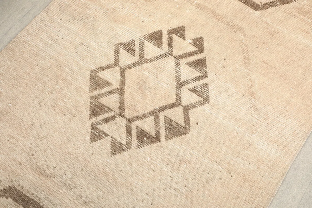 Close-up showing the central geometric motif with subtle wear and texture on the rug.
