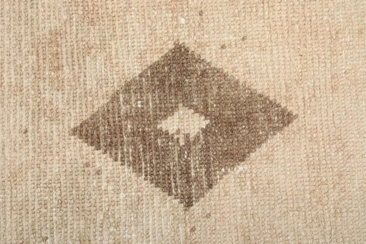 Macro detail of the diamond-shaped motif, highlighting the wool pile and knotting.