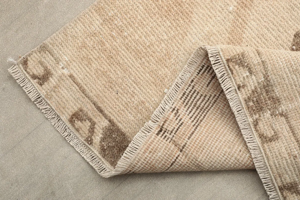 Corner of the rug folded to show the hand-knotted construction and cotton foundation.