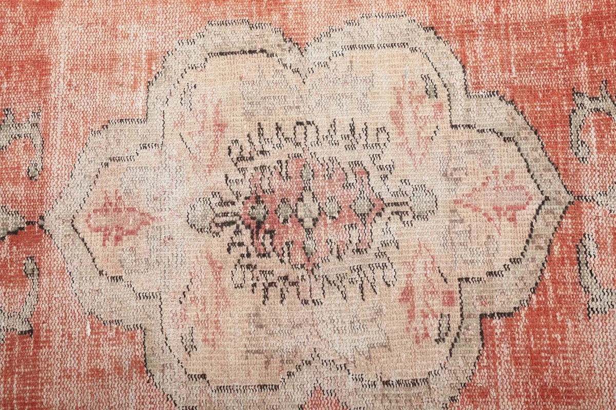 Detailed view of the intricate design within the central medallion of the rust rug.