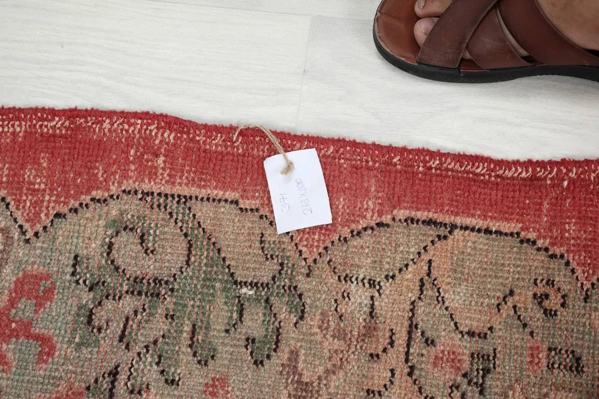 Detail of the rug's edge with a tag, showing the wool pile and border colors.