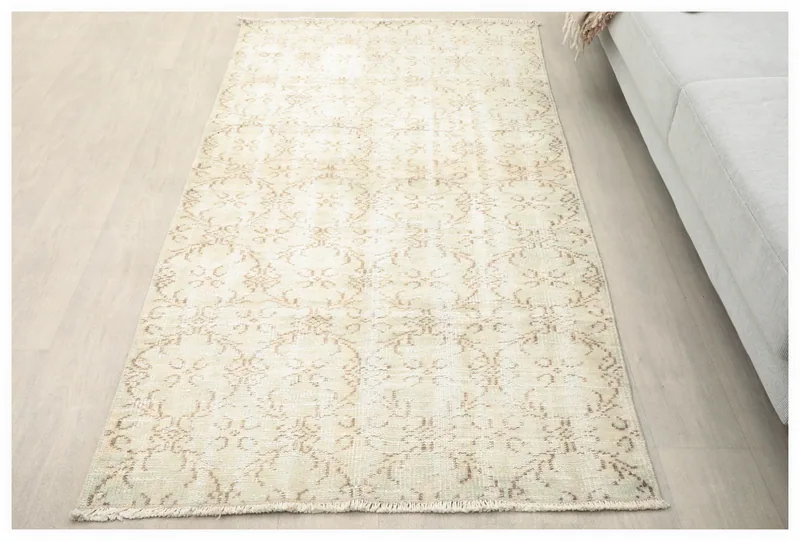 Full overhead view of the beige floral vintage Anatolian rug on a white background.