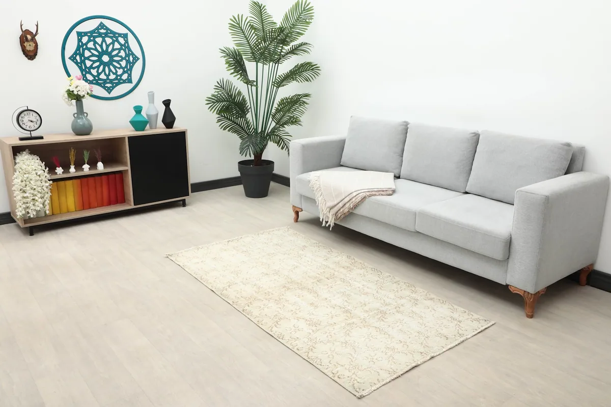 Beige floral rug placed in a living room setting with a light gray sofa and modern decor.