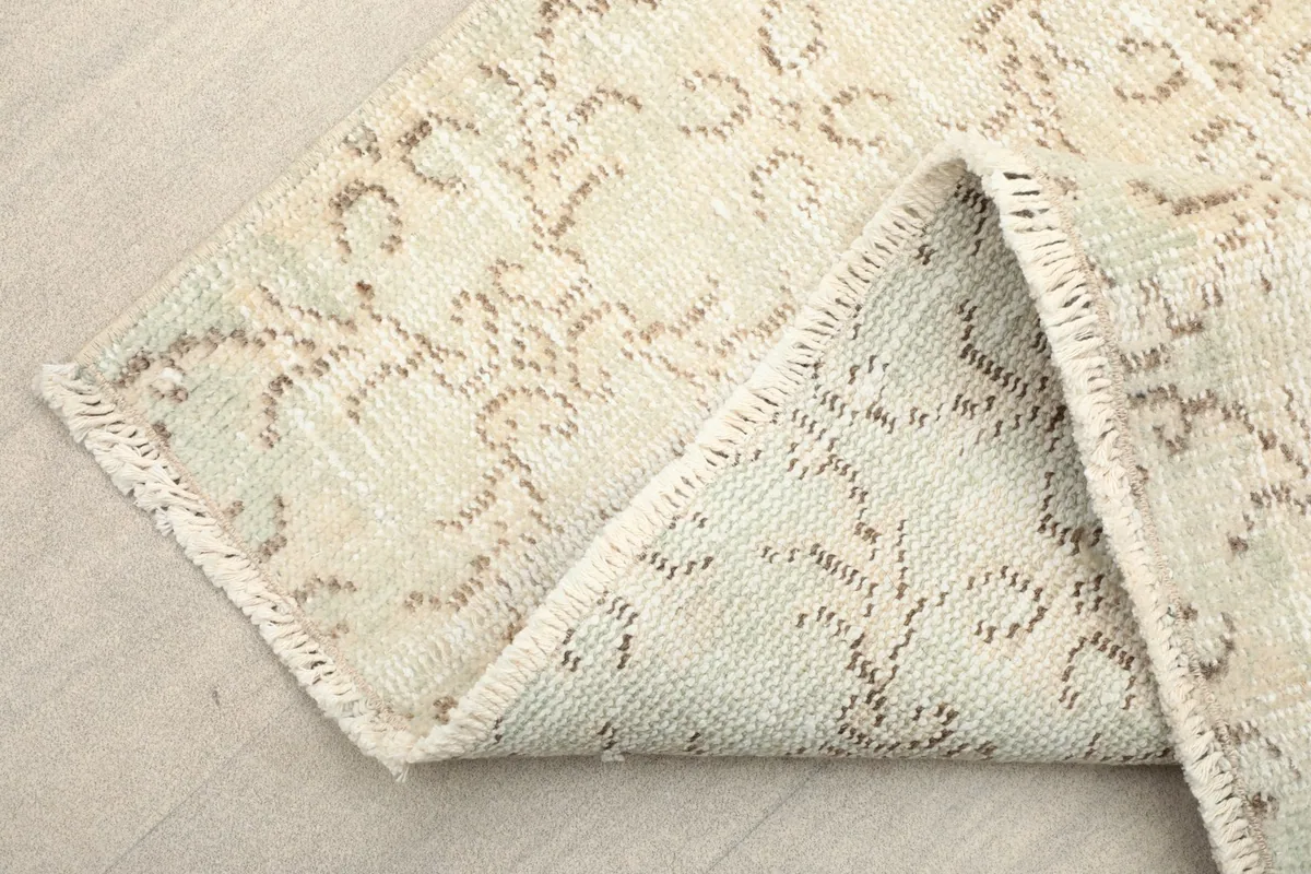 Folded corner of the rug, revealing the cotton foundation and the reverse side of the pattern.