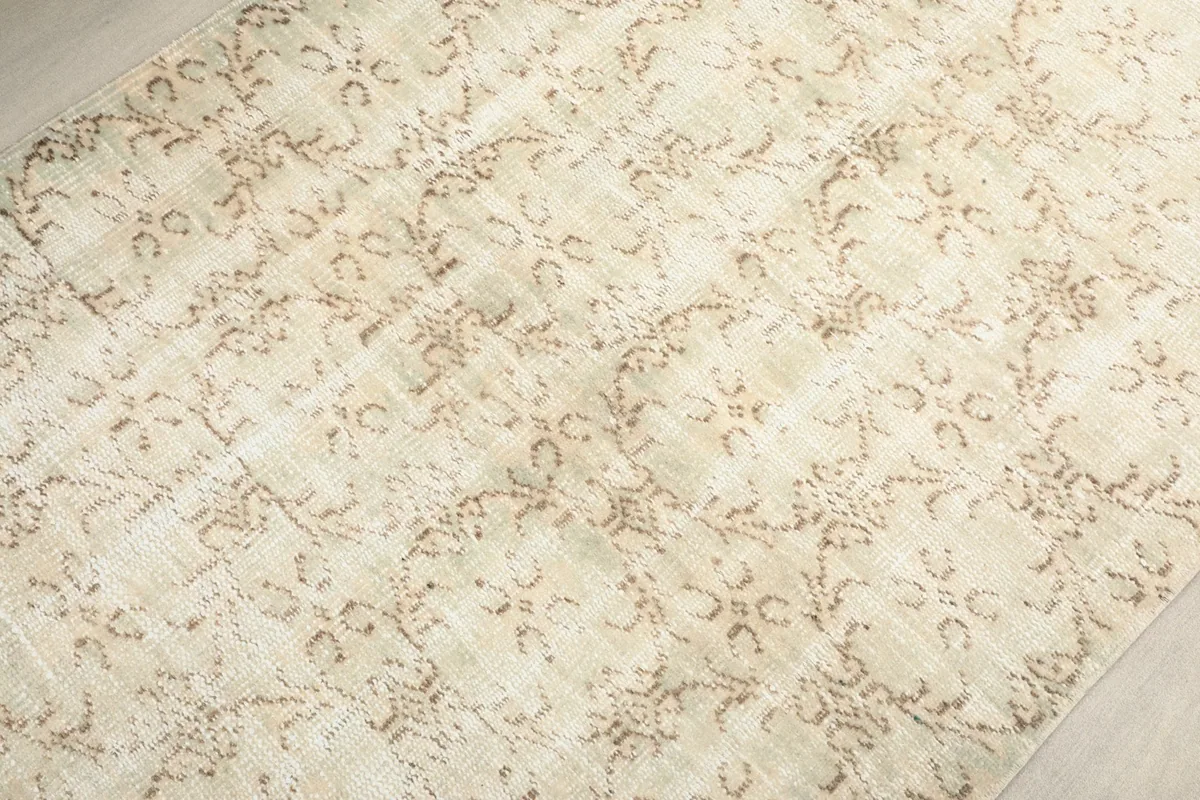 Overhead detail of the rug's surface, focusing on the intricate tan floral motifs.