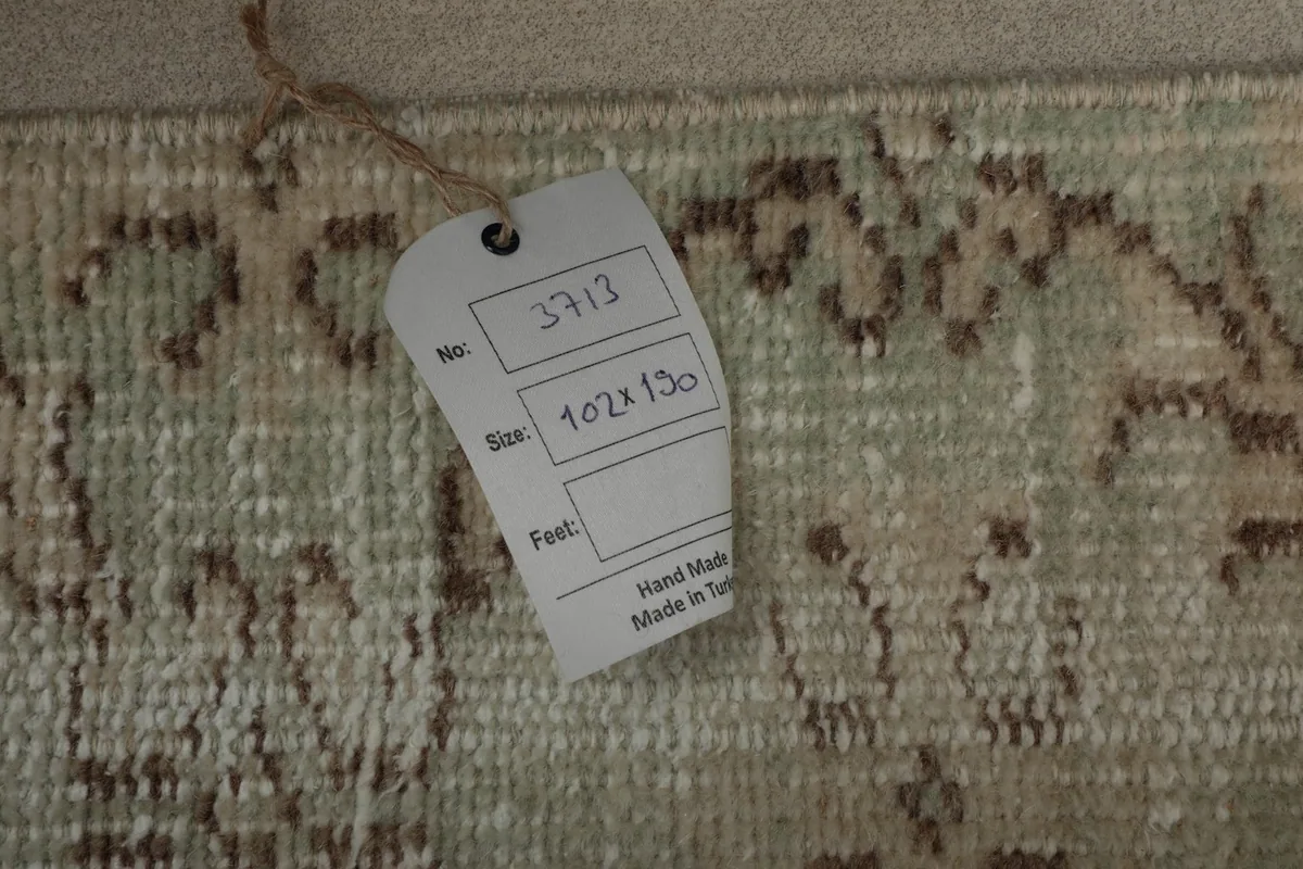 Close-up of a tag on the rug, indicating its size in centimeters and origin as hand-made in Turkey.