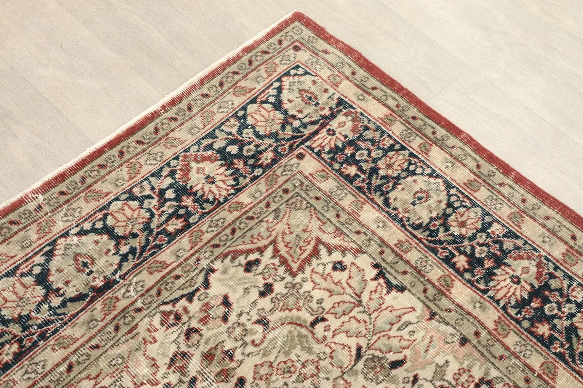 Corner view of the red and navy vintage rug, showing the border pattern