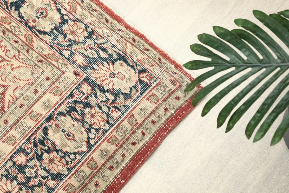 Detail of the navy and red border with subtle floral motifs and a plant accent