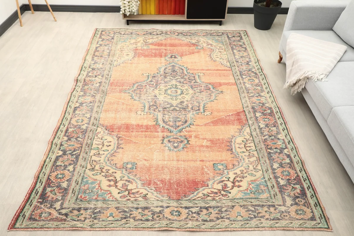 Vintage orange medallion rug placed in a living room setting with a light gray sofa.