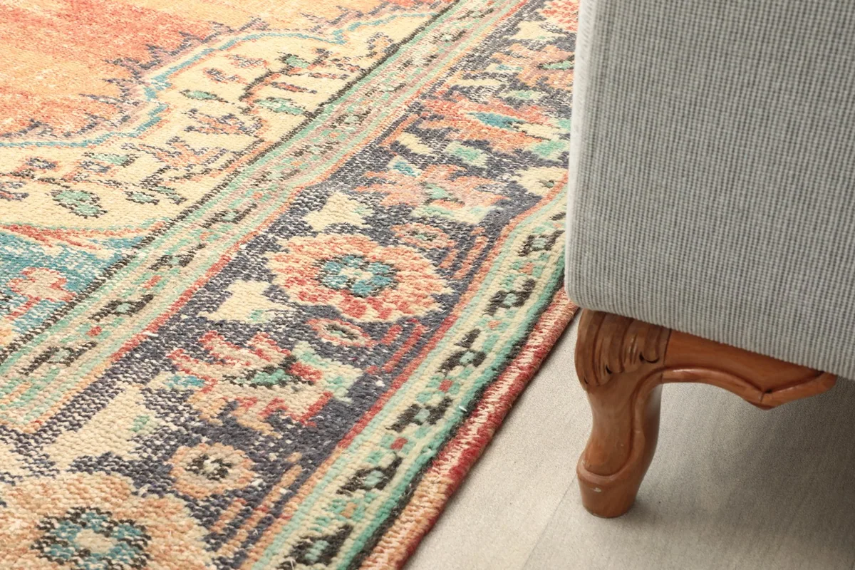 Partial view of the rug extending under a sofa, showing its scale in a living space.