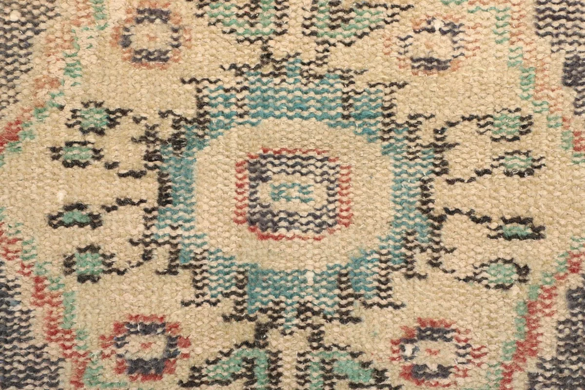 Macro detail of the rug's fibers and knotting, revealing the wool texture and color blend.