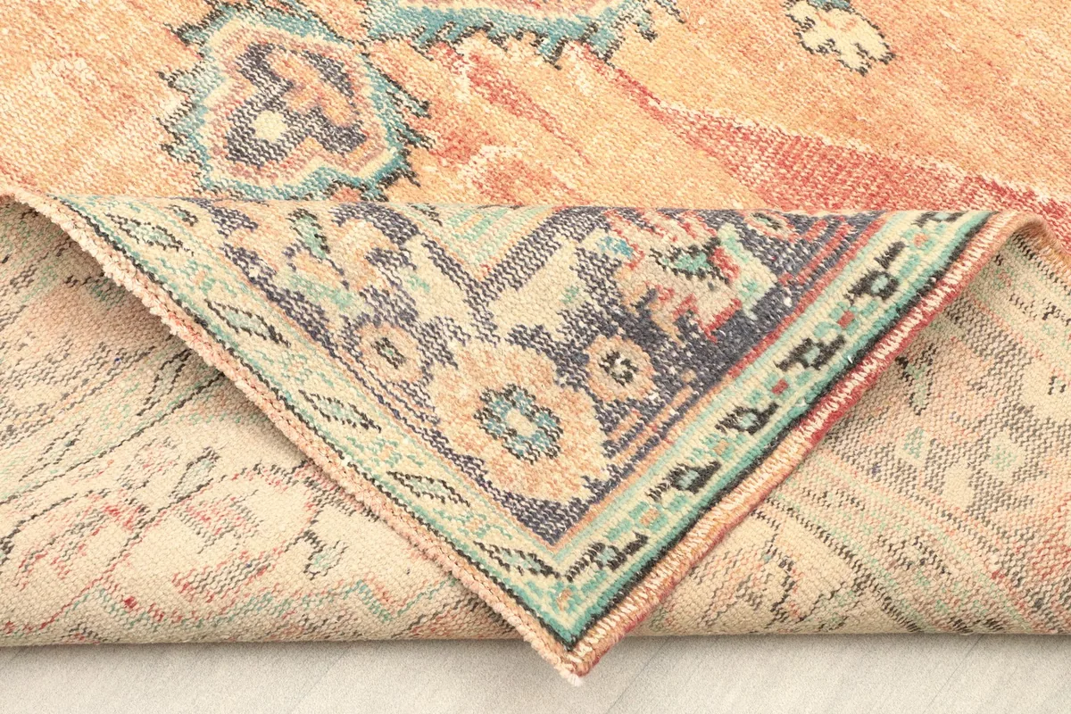 Folded corner of the rug, displaying the reverse side and the hand-knotted construction.