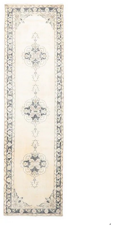Full overhead view of an ivory and navy vintage Anatolian runner rug on a white background.