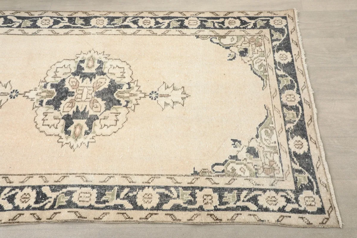 Close-up of the rug's end, highlighting the navy border and central floral medallion.