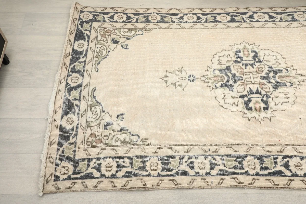 Detail view of the rug's border and one of the stylized floral patterns in ivory, navy, and olive.