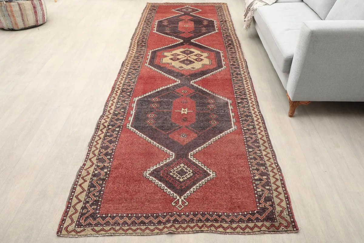 Vintage red runner rug with geometric patterns in a modern room setting, showing its length and scale.