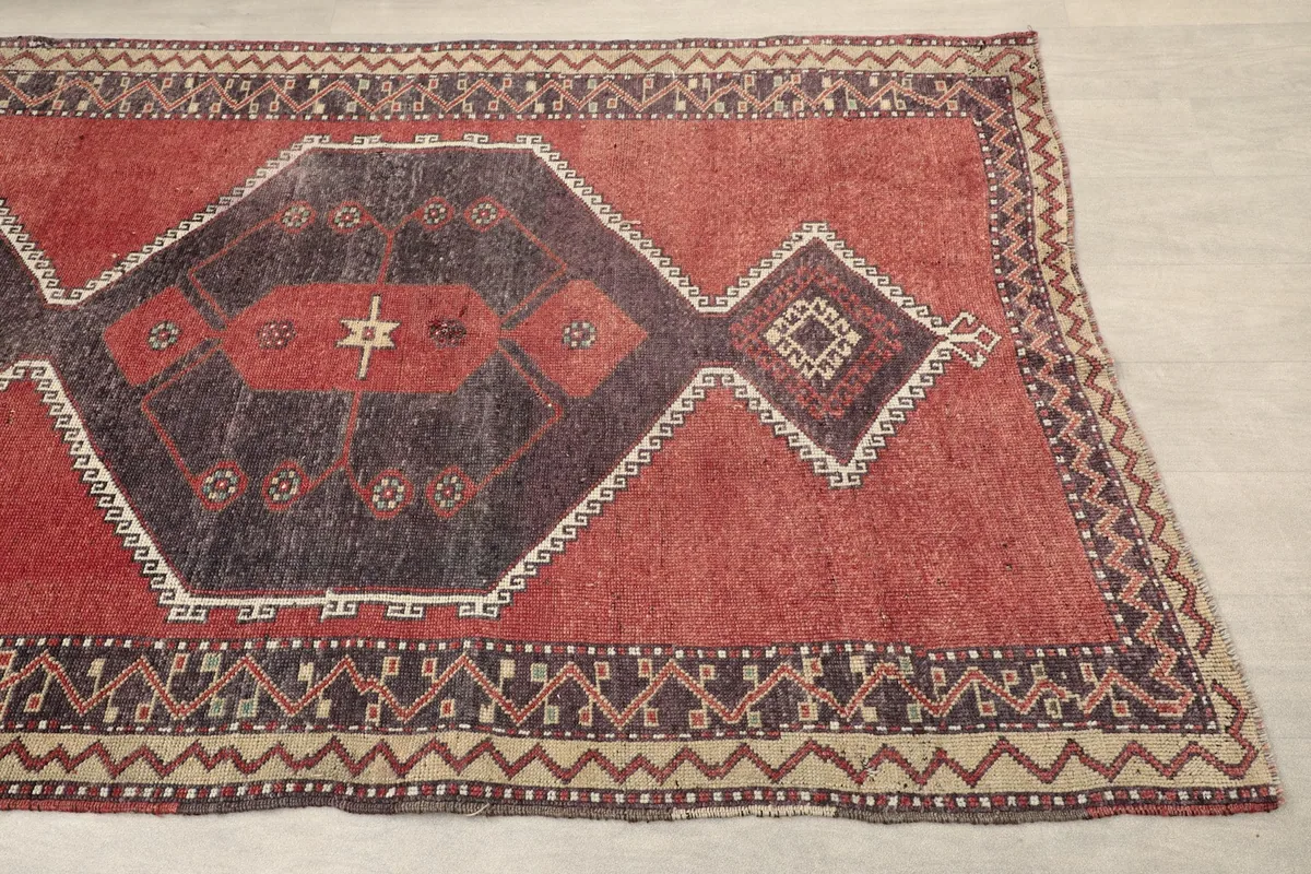 Close-up of the red field and charcoal geometric pattern with beige and ivory accents near the border.