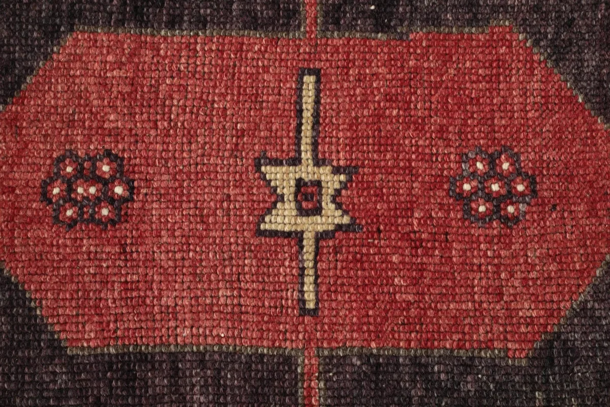 Macro shot of the hand-knotted wool pile, revealing the texture and subtle color variations within the charcoal and red.