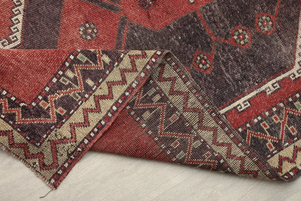 Folded corner of the runner rug, showing the reverse side and the construction of the hand-knotted wool pile.