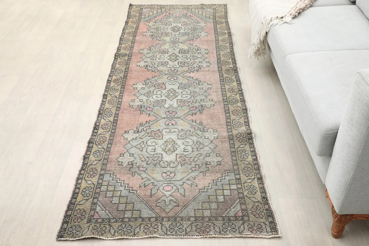 Overhead view of the rose runner placed in a room setting next to a light gray sofa.