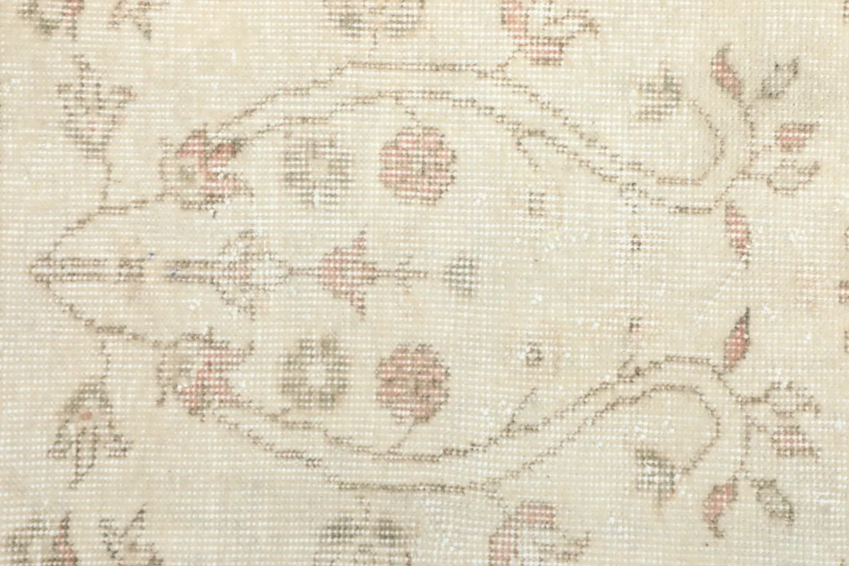 Close-up of a specific floral motif within the ivory field, showing color variations and weave
