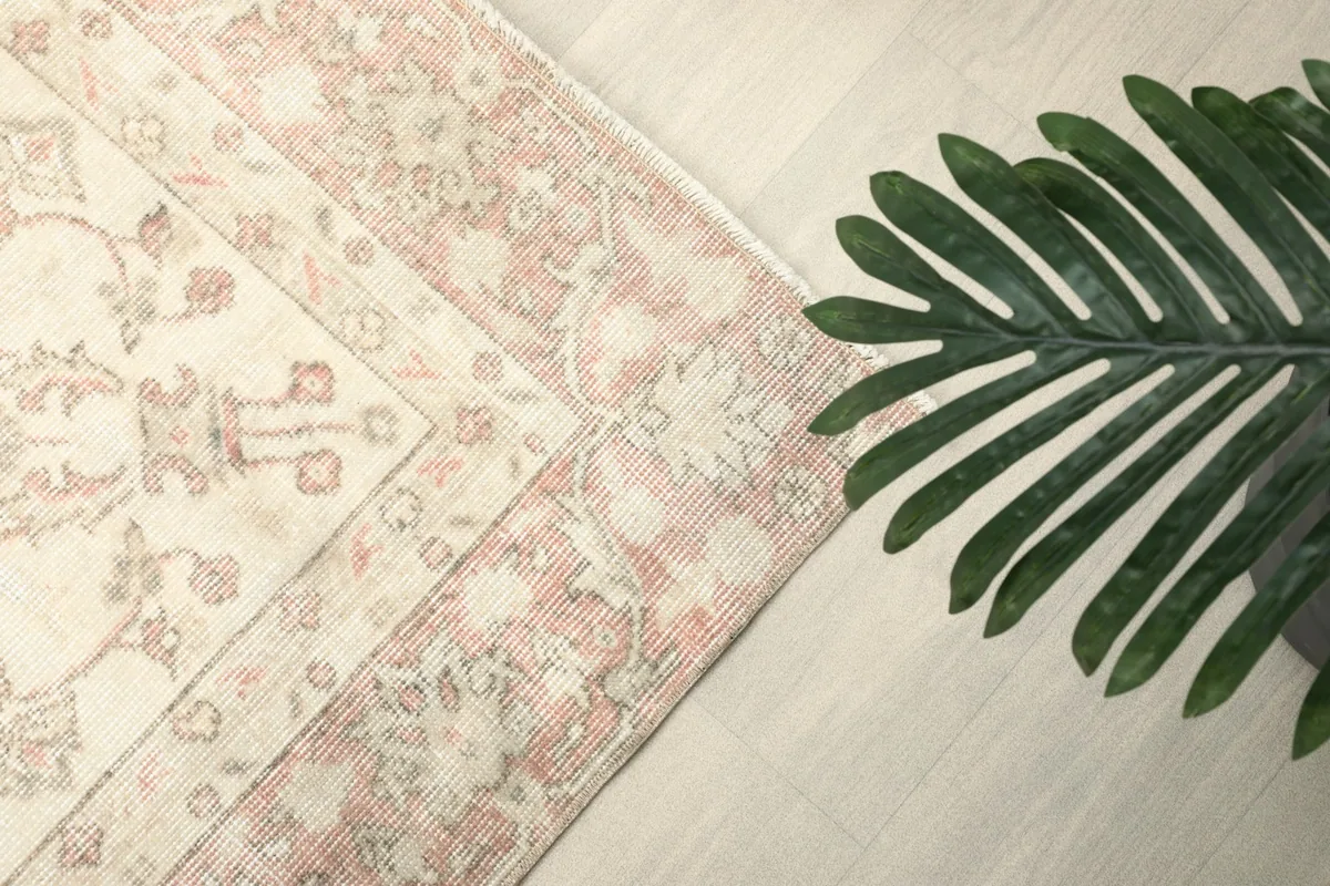 Detail of the rose-colored border pattern and a portion of the ivory field, with a plant accent