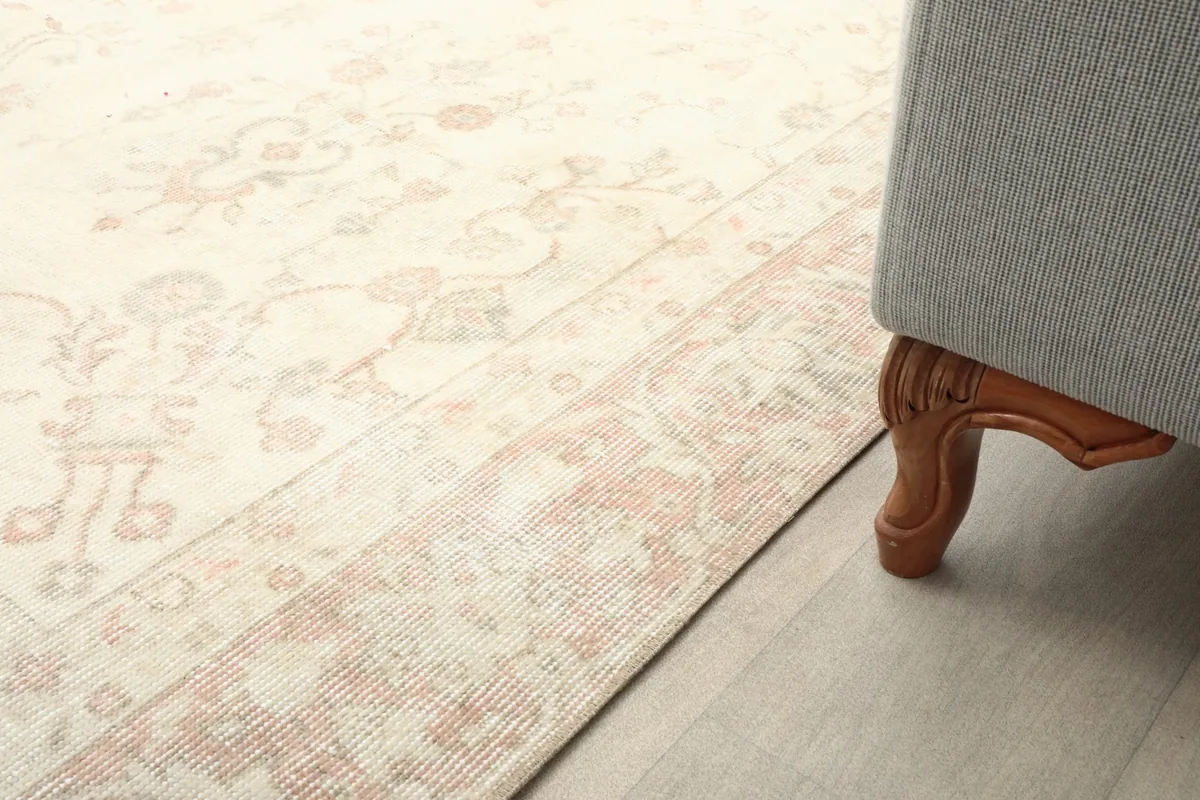 Close-up of the rug's low pile and border pattern, seen next to the leg of a sofa