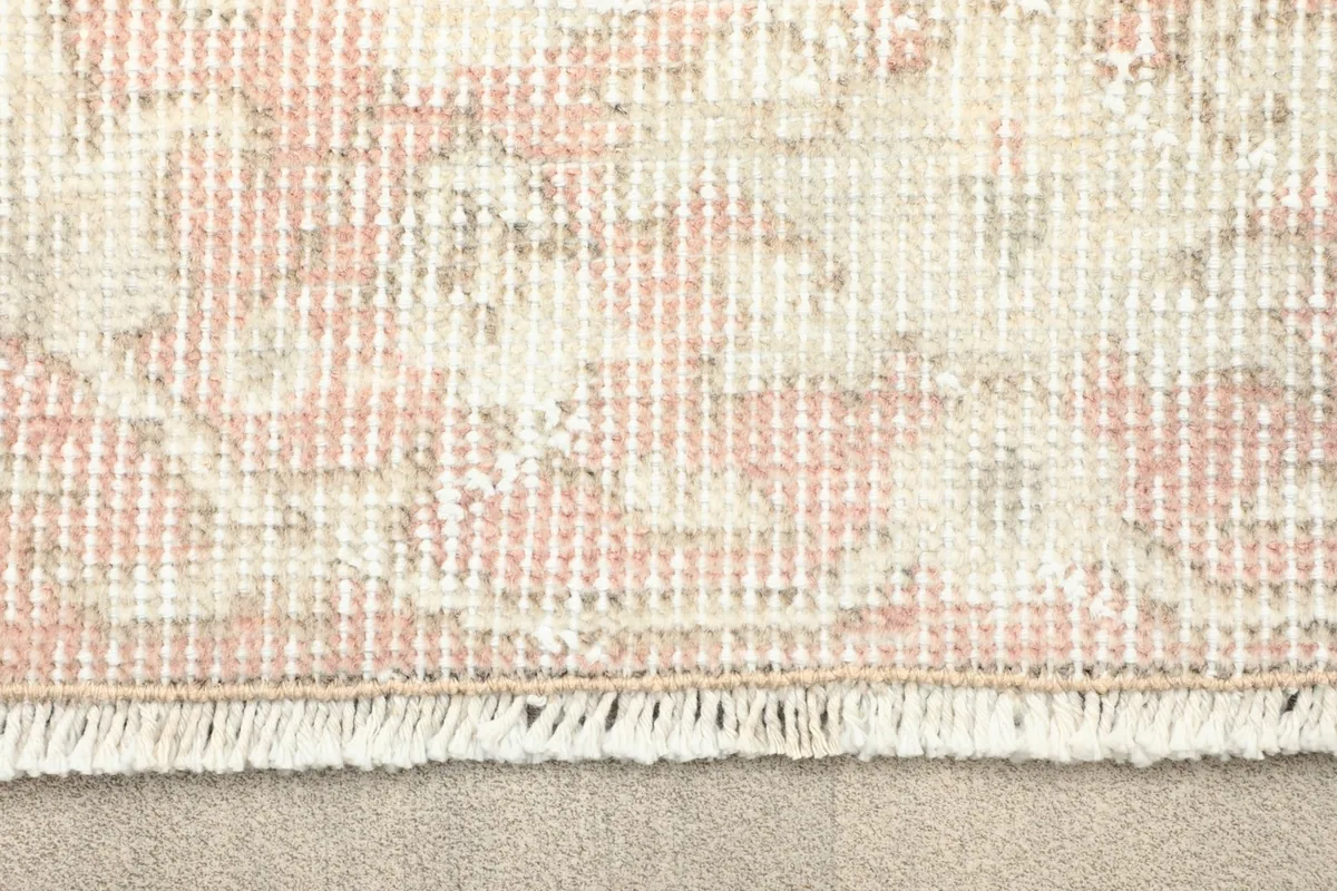 Close-up detail of the short, subtle fringe and the border pattern of the vintage wool rug