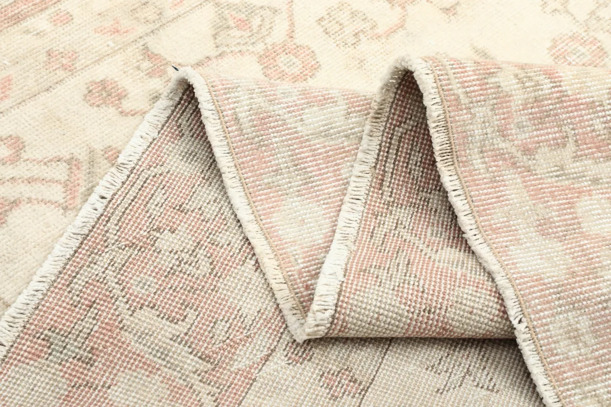 Close-up of the rug folded, revealing the texture of the low wool pile and the foundation