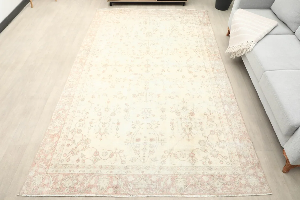 Overhead view of the ivory and rose vintage rug in a living room setting with a light gray sofa