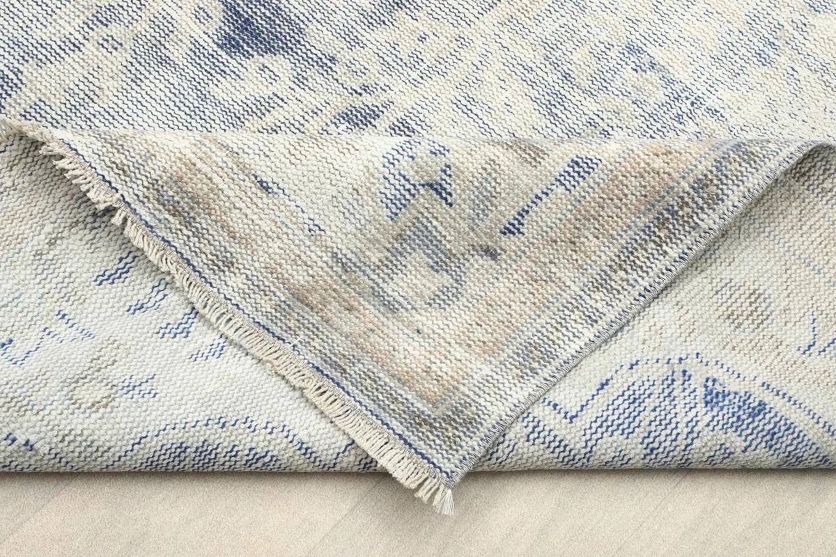 Folded corner of the rug revealing the reverse side of the hand-knotted cotton foundation.