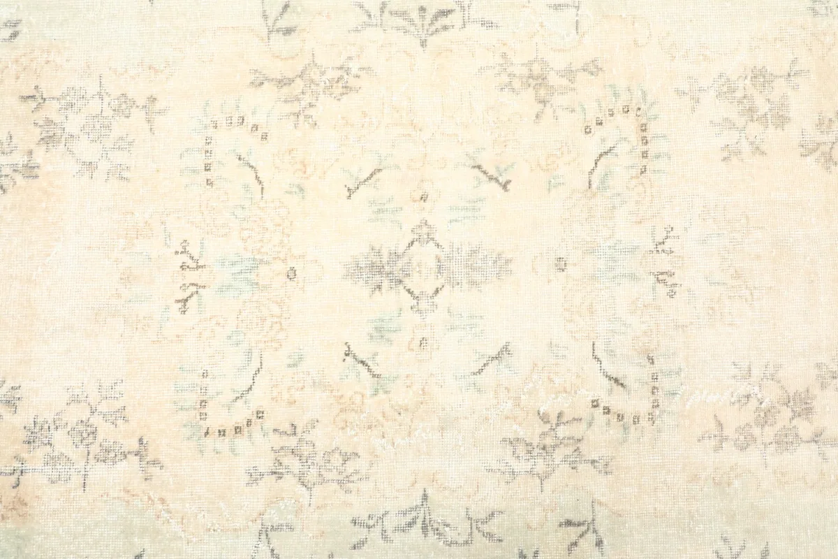 Close-up of the central area of the rug, revealing faded floral and medallion-like motifs