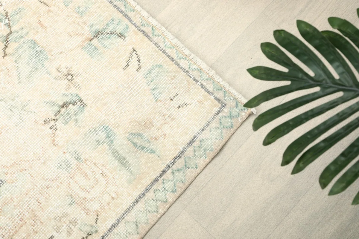 Detailed view of the rug's border and a portion of the main field with a plant accent