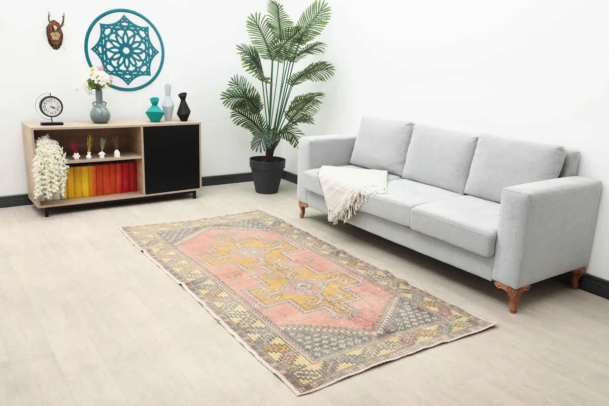 Medium shot of the rose and gold geometric rug placed in a living room with a sofa.