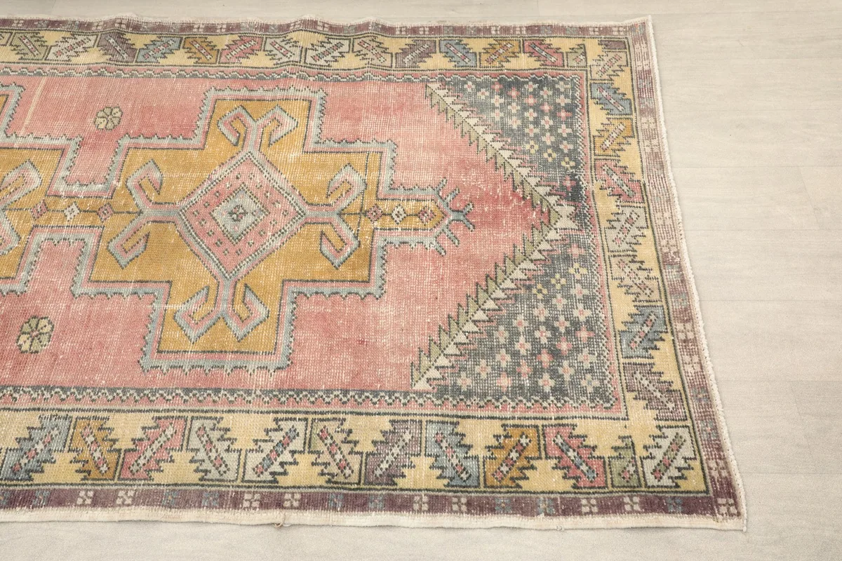 Close-up of the rug's rose and gold central field with a gray and tan border.