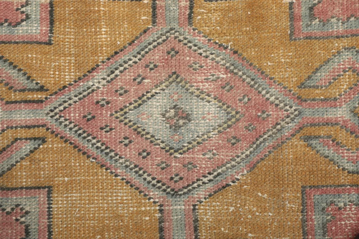 Macro shot of a central geometric motif, highlighting the hand-knotted wool texture.